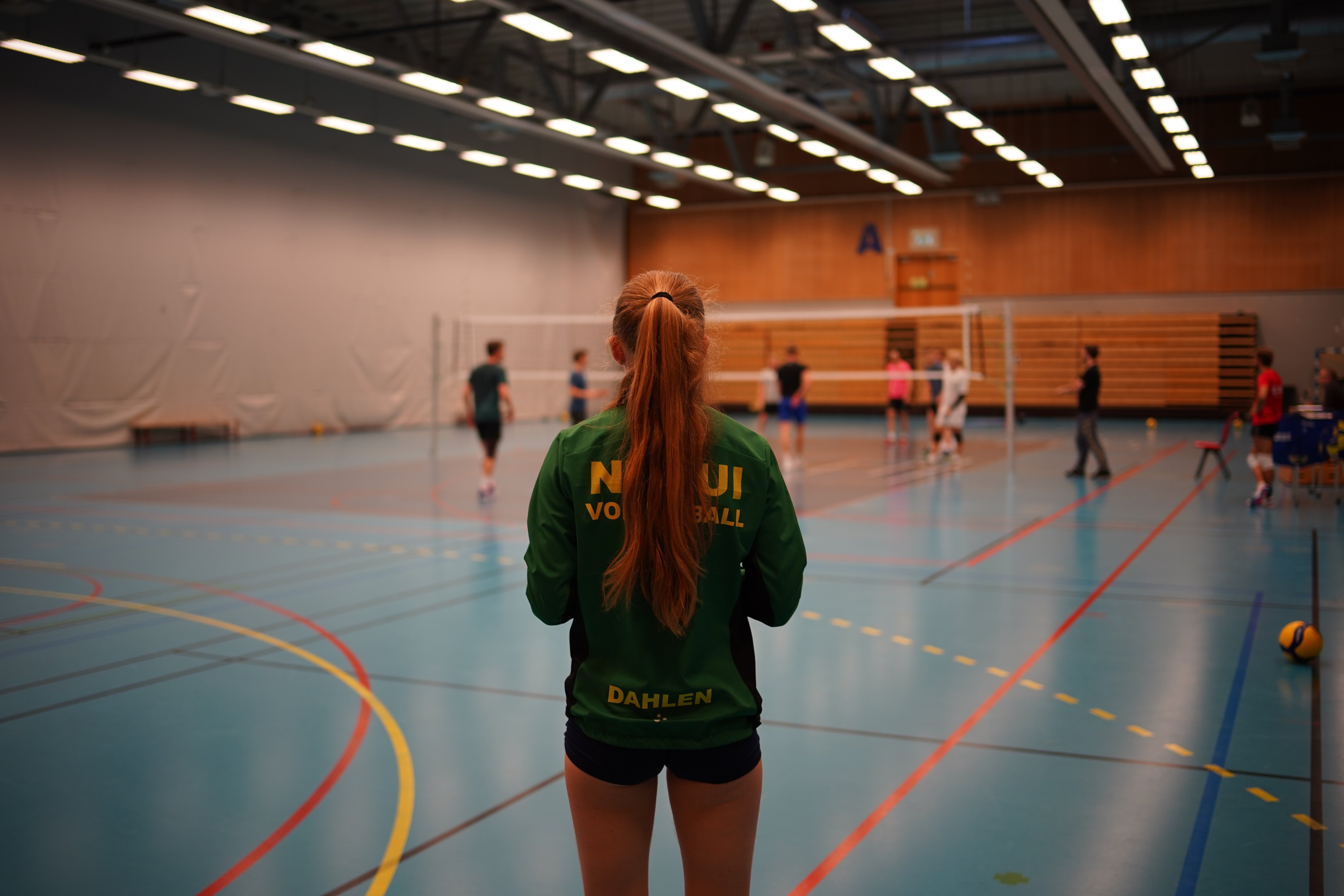Volleyballtrening i hallen med en NTNUI-spiller i forgrunnen