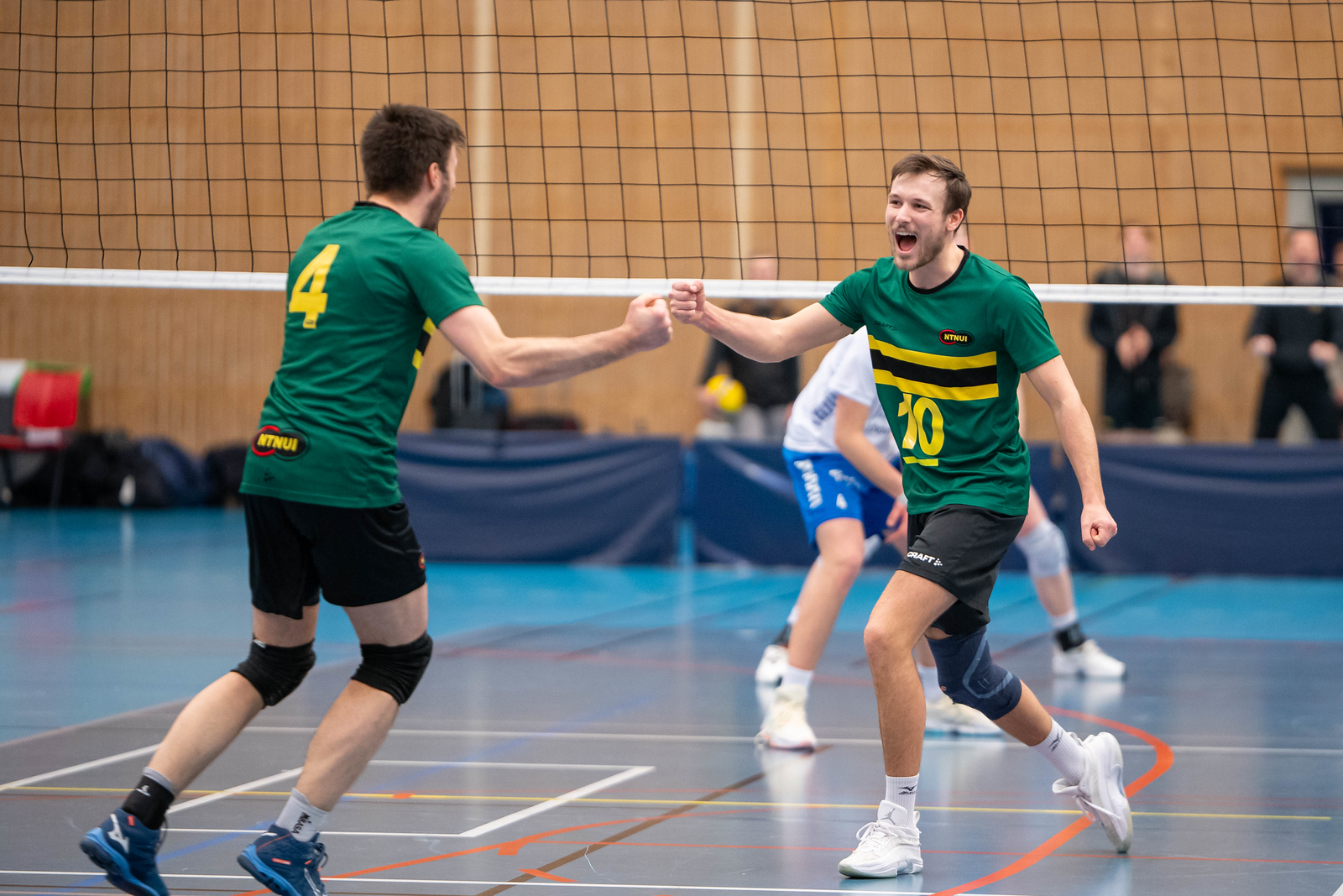 To NTNUI-spillere feirer sammen ved volleyballnettet
